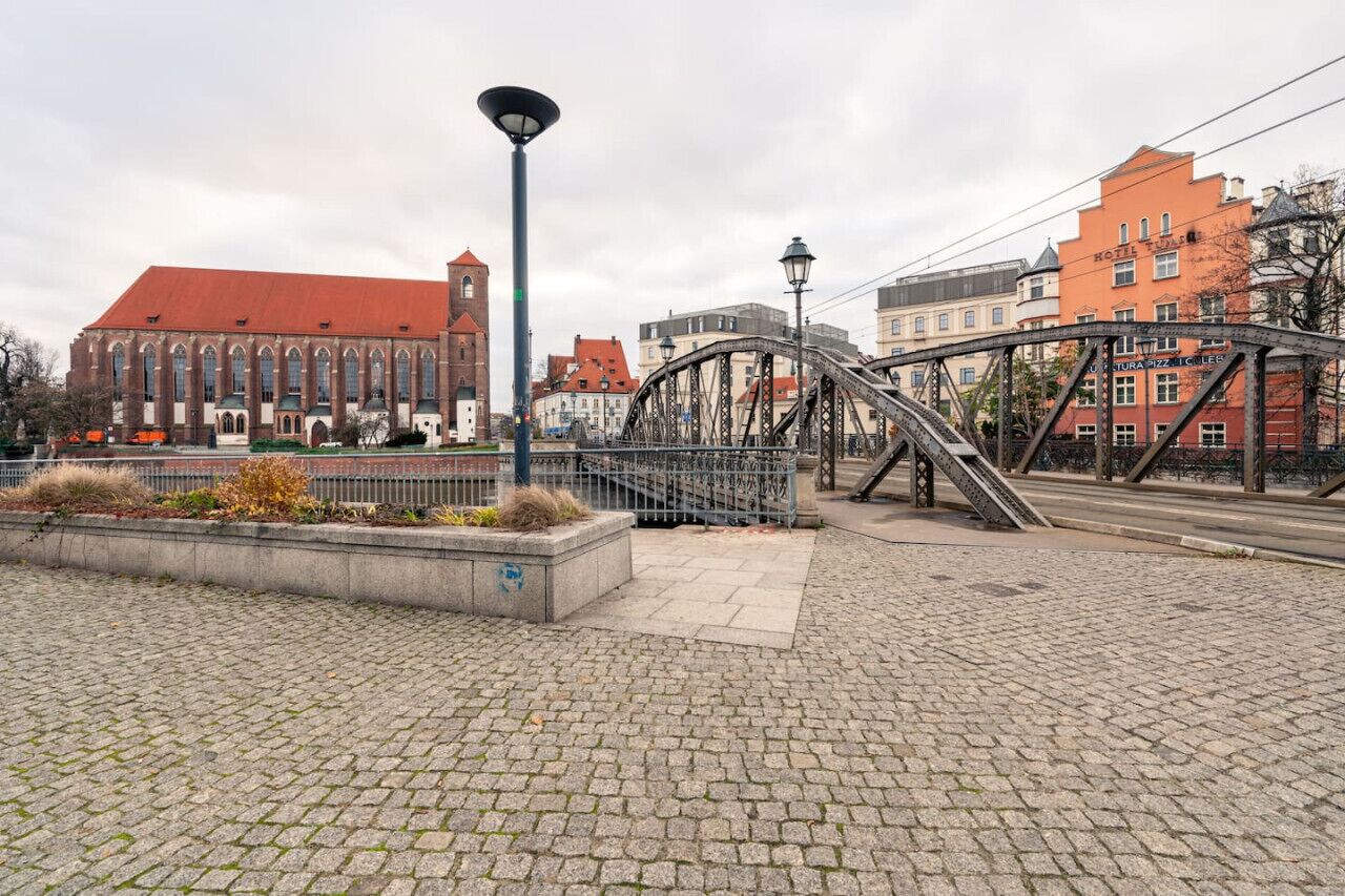 Ein Pflasterplatz mit einem historischen Gebäude, das ein rotes Dach und Bogenfenster hat.