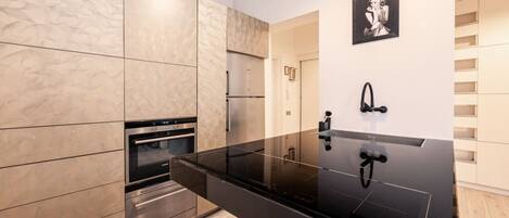 A modern kitchen with a black countertop, stainless steel appliances, and a marble backsplash.