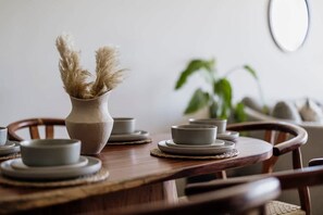 A dining table with ceramic plates, a vase with dried pampas grass, and a potted plant. - The Mara 2 Bedroom Amira Beach Club Access! (Tulum)