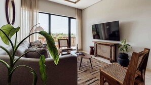 Uma sala de estar moderna com sofá, mesa de centro, televisão e janelas amplas.