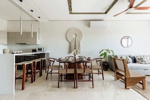 Una cocina moderna con comedor, que presenta una mesa redonda de madera, sillas a juego y un ventilador de techo.