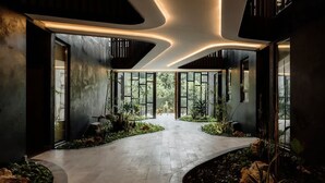 Interior moderno com caminho sinuoso, janelas amplas e plantas dentro de casa.
