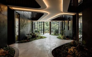 A modern interior with a curved pathway, large windows, and indoor plants. - The Mara 2 Bedroom Amira Beach Club Access! (Tulum)