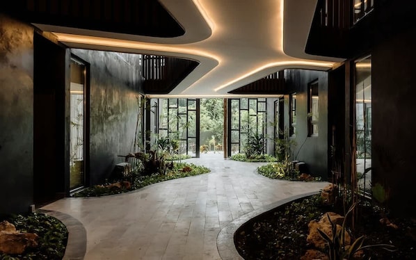 Un interior moderno con un camino curvo, ventanas amplias y plantas de interior.