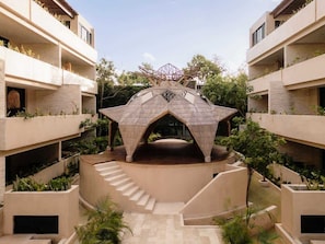A modern building with a central open space, surrounded by balconies with plants.