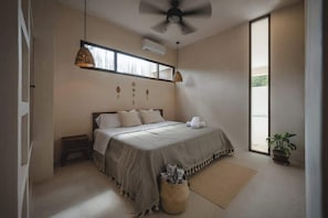 Un dormitorio con una cama, ventilador de techo, ventana y una planta en maceta.