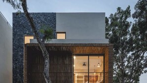 A modern two-story house with a stone facade, large windows, and a visible interior with a dining area. - Maki Mystical Tulum Villa Beach Club Access (Tulum)