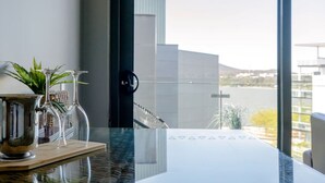 A modern room with a large window, a marble table, and a view of a building and landscape. - Modern studio w/t wifi & parking (Kingston)