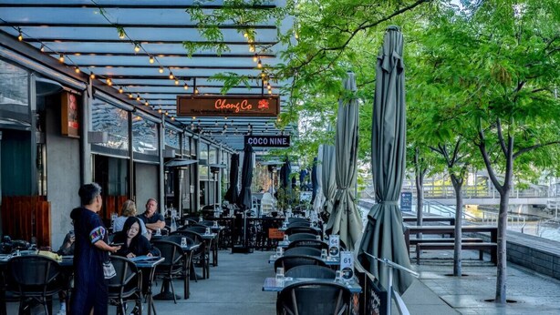 An outdoor dining area with tables and chairs, a covered walkway, and a sign for 'Chong Co'. - Modern studio w/t wifi & parking (Kingston)