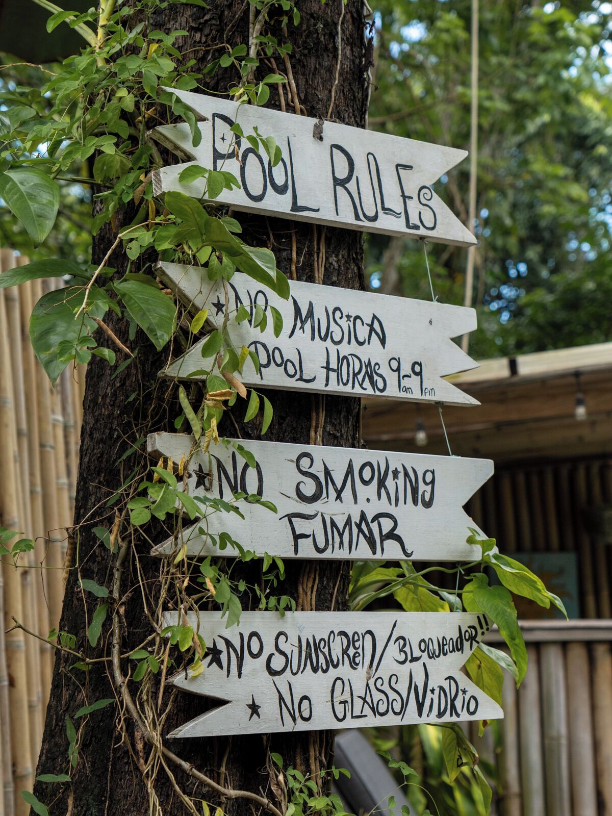 A sign with pool rules including no smoking, no sunscreen/glasses, and a pool hours notice.