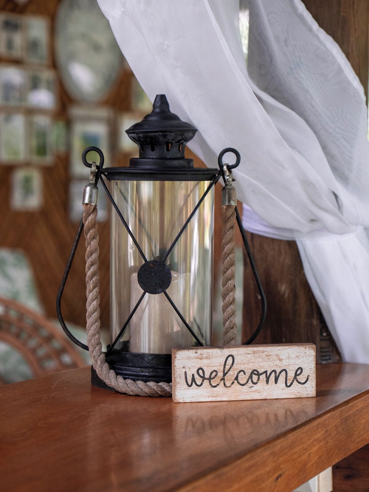 A lantern with a rope handle and a 'welcome' sign on a wooden surface.