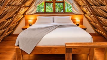 Una cama en una habitación con techo y paredes de madera, una ventana con cortinas y dos lámparas de noche.
