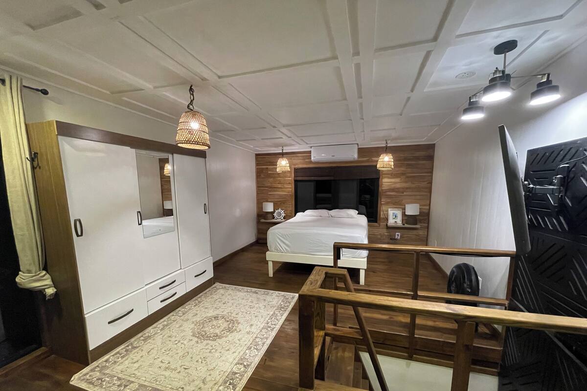Een slaapkamer met een bed, een kledingkast, nachtkastjes en een houten vloer.