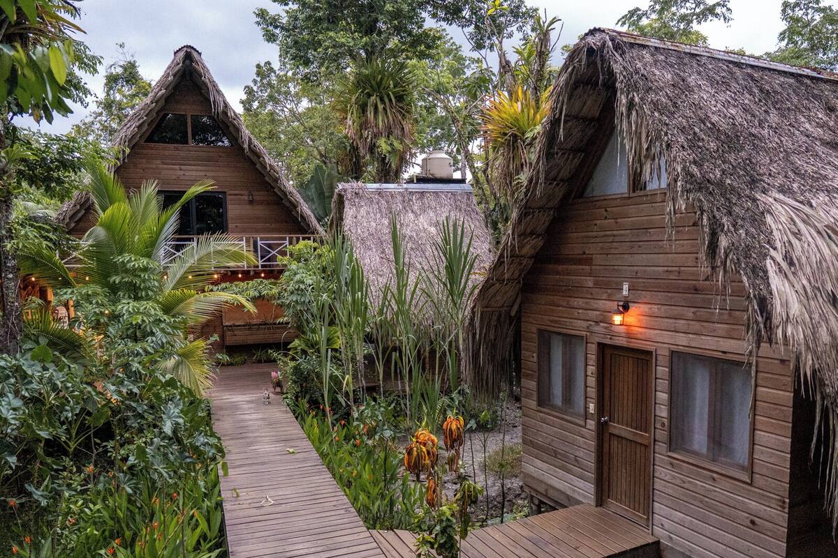 Een rieten huisje met een houten terras en een tuinpad.