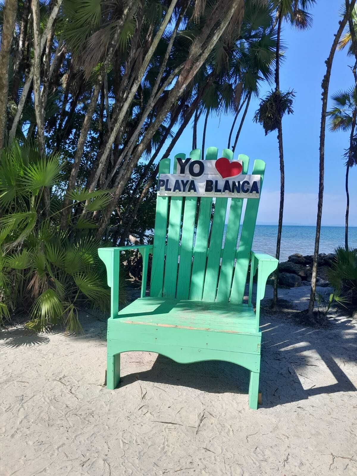 A green beach chair with a sign that reads "YO LOVE PLAYA BLANCA".