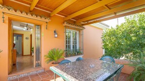 Portico coperto con tavolo e sedie, una porta che dà all'interno e una finestra con inferriate.
