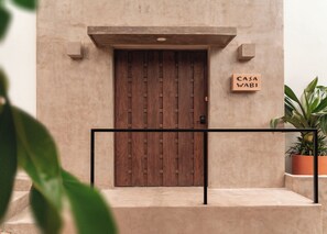 Une porte en bois sur laquelle est accrochée une enseigne indiquant « CASA WABI ».