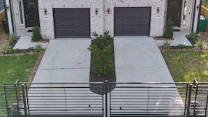 A two-story residential building with a symmetrical facade, two garages, and a small front garden. - Chic Modern Getaway: Indoor Basketball, Huge TVs, & Smart Living (Houston)
