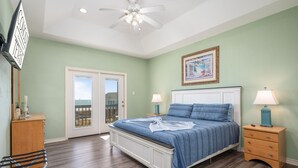 A bedroom with a bed, nightstands, a dresser, a chair, and a ceiling fan.