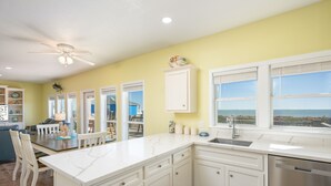 A kitchen with white cabinetry, a marble countertop, and a view of the ocean.