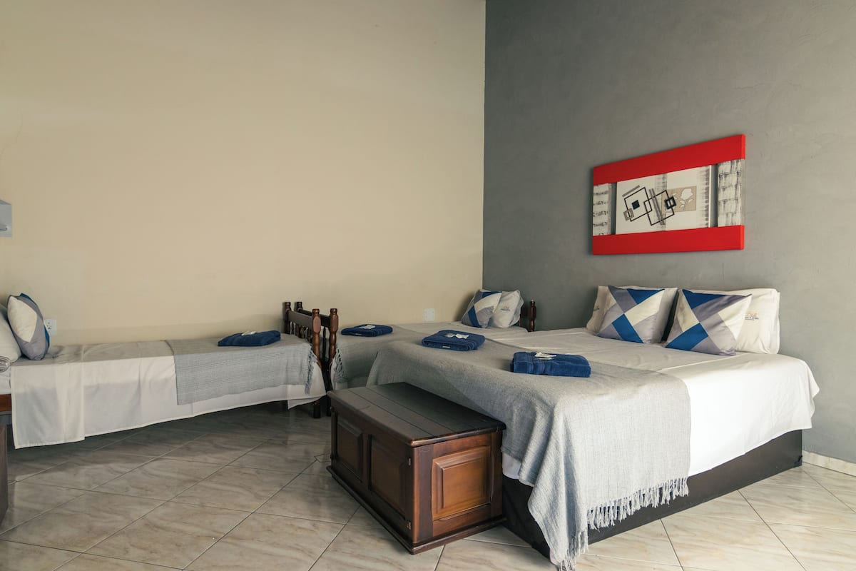 Ein Hotelzimmer mit zwei Betten, einer hölzernen Bank und einem an der Wand befestigten Kunstwerk.