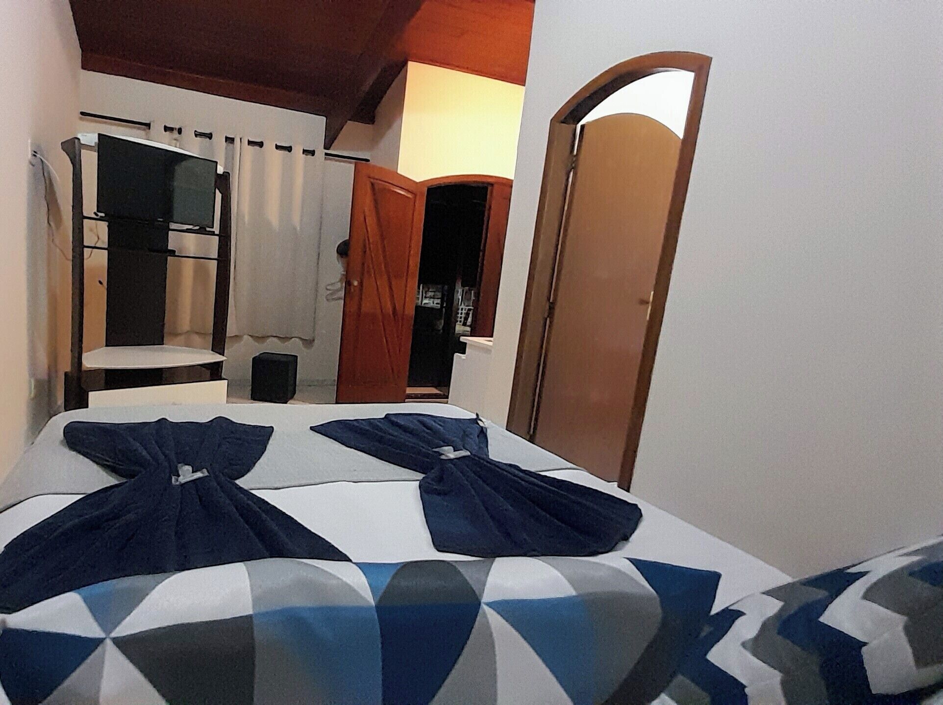 A bedroom with two beds, a wooden wardrobe, a small table, and a mirror.