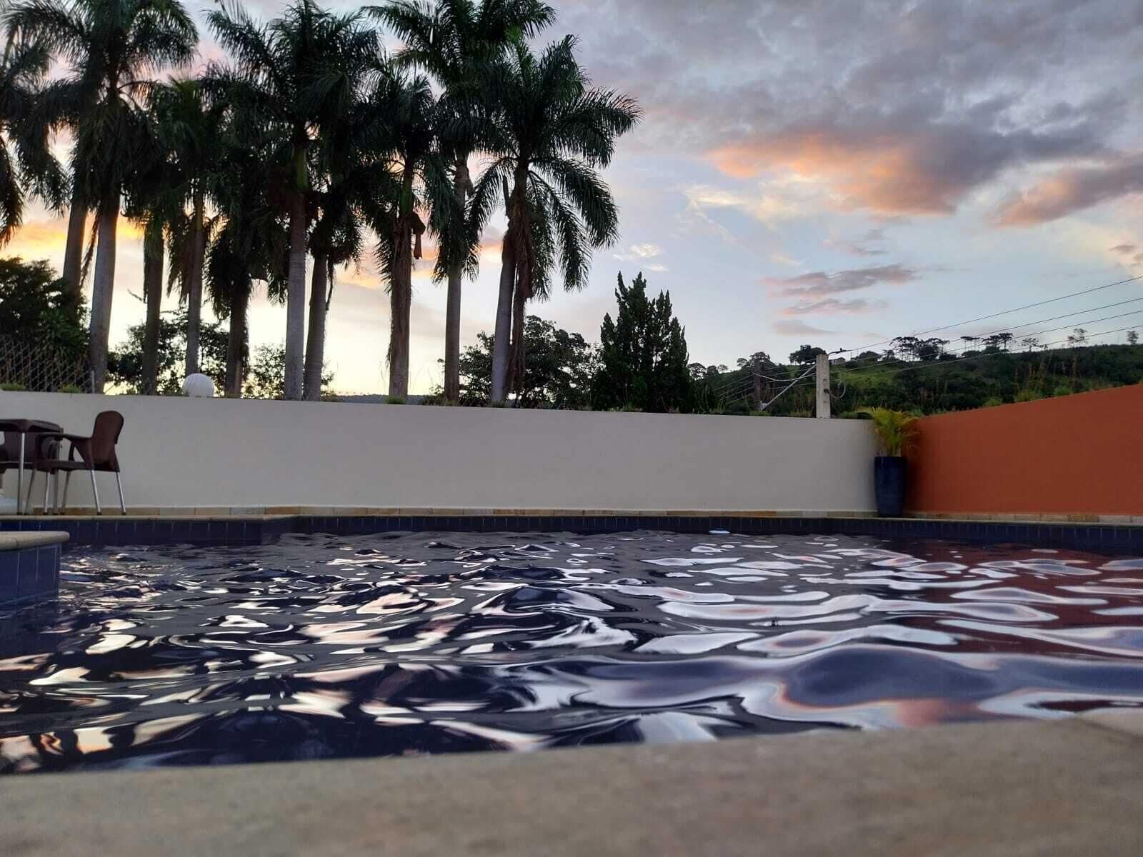 A swimming pool with a unique reflective surface, surrounded by palm trees and a white wall.