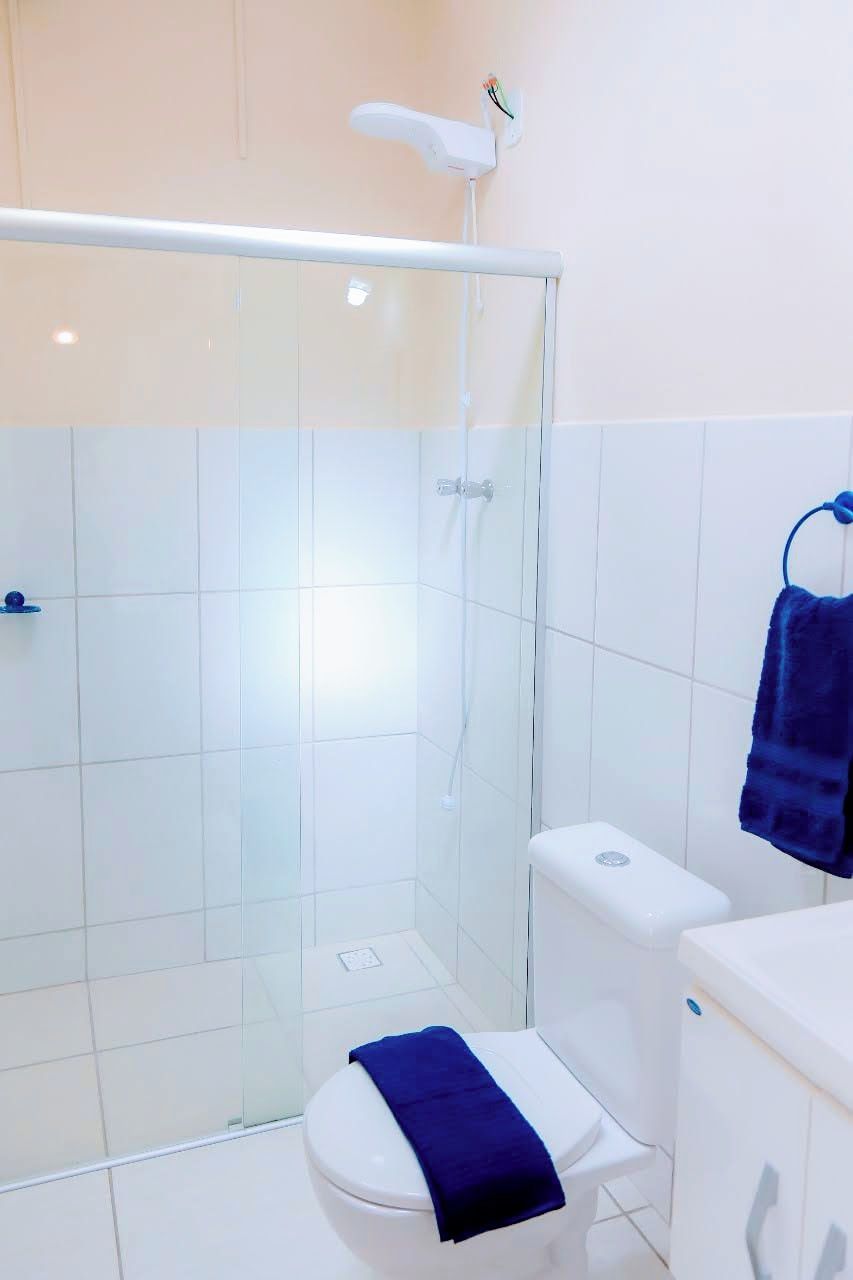 Een badkamer met een douchecabine van glas, een wit toilet en een blauwe handdoek aan een rek.