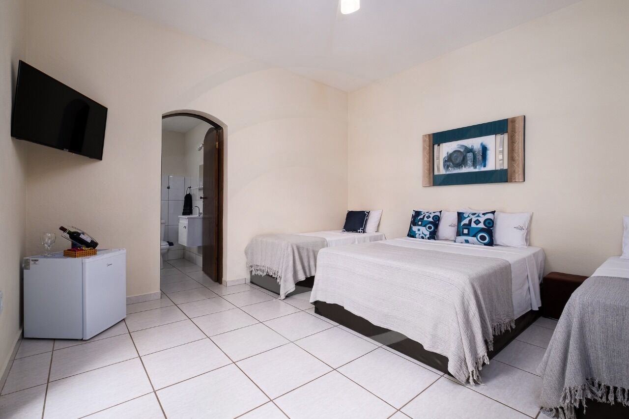 Habitación de hotel con dos camas, un televisor, un refrigerador y un cuadro en la pared.