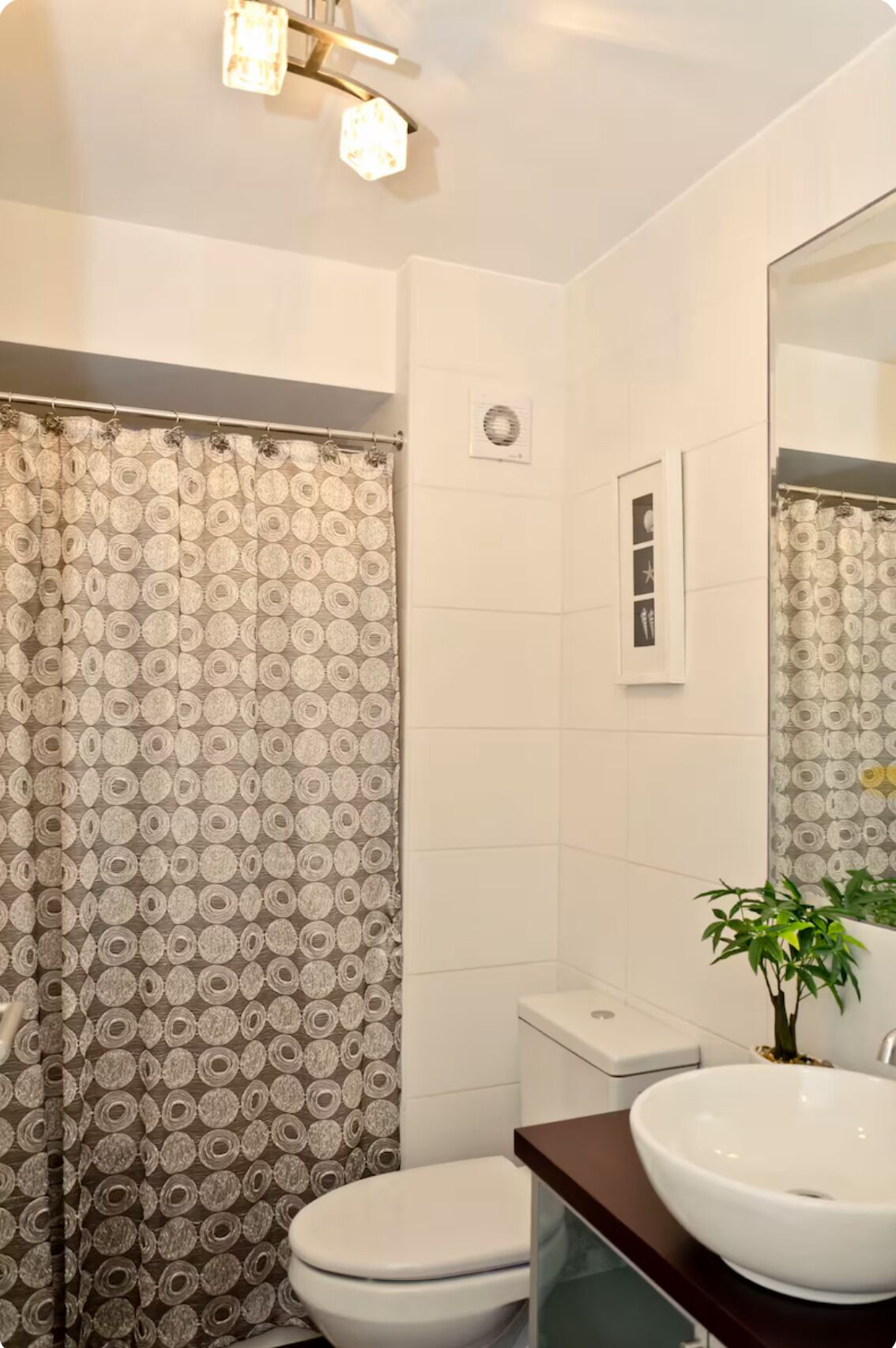 A bathroom with a toilet, a sink, and a shower curtain with a circular pattern.