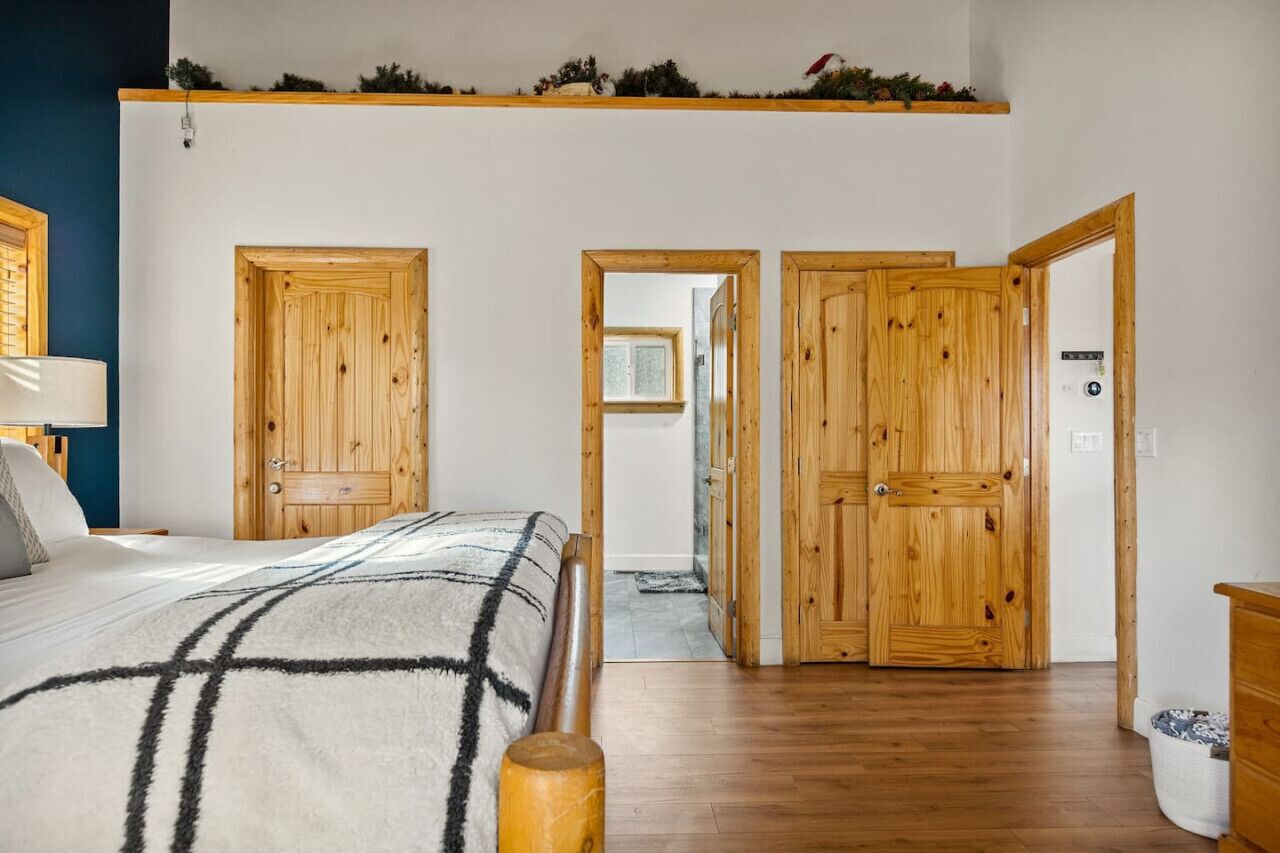 Un dormitorio con cama, armario de madera y un pasillo que conduce a otra habitación.