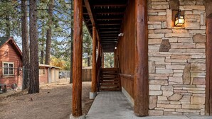 A wooden covered walkway leading to a stone building with a lantern.