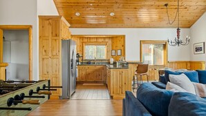 A cozy kitchen with wooden cabinets, a central island, and a blue sofa in the living area.