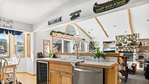 Une cuisine avec des meubles en bois, un réfrigérateur en acier inoxydable et un mur décoré avec des pierres apparentes.