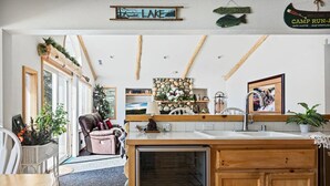 Une cuisine avec des poutres en bois, un mur en pierre, un évier et un réfrigérateur.