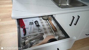 Eine Küche mit Marmorarbeitsplatte, Spüle aus Edelstahl und einer Schublade mit Besteck.