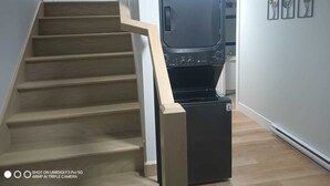 Eine Treppe führt zu einem Küchenbereich mit einem schwarzen Kühlschrank und einem Fernseher.