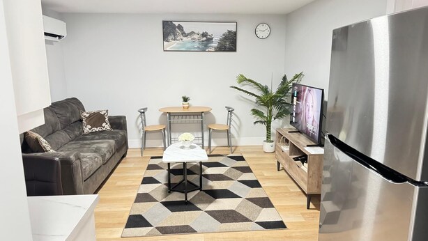 Ein modernes Wohnzimmer mit Sofa, Couchtisch, Fernseher und Kühlschrank.