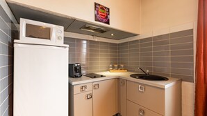 A compact kitchen with a microwave, coffee maker, and sink.