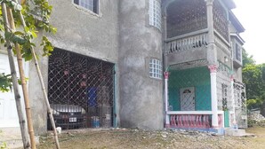 Un edificio de dos pisos con balcón, un porche cubierto y garaje.