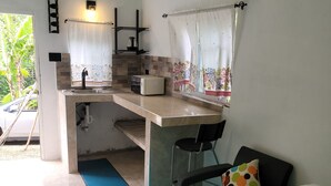 Una habitación funcional con kitchenette, cama y vistas al exterior.