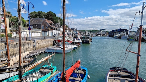 A harbor with boats docked, a stone wall, and buildings in the background. - La Tour Vauban - Vue sur le port (Port-en-Bessin-Huppain)