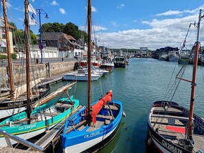 Ein Hafen mit vertäuten Booten, einer Steinmauer und Gebäuden im Hintergrund.