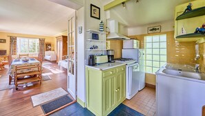 Una cucina funzionale con angolo ristoro, dotata di piano cottura, lavello e scaffali aperti con diversi oggetti.