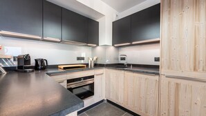 Una cucina moderna con mobili scuri, un piano di lavoro in legno ed elettrodomestici integrati.