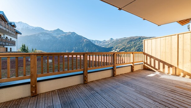 Una terrazza in legno con ringhiera che si affaccia su un paesaggio montuoso.