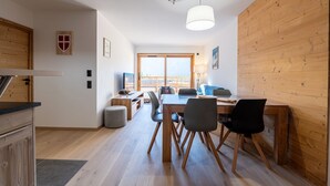 Una cucina moderna con armadietti in legno, un'area pranzo con tavolo e sedie, e un'ampia finestra che offre luce naturale.