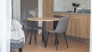 A modern kitchen with wooden cabinets, a round table, and two grey chairs. - L'Essentiel du KM22 - Appt avec terrasse et jardin (Petit-Bourg)