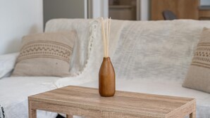 A wooden table with a brown vase and reed diffuser in a living room. - L'Essentiel du KM22 - Appt avec terrasse et jardin (Petit-Bourg)