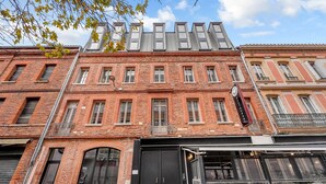 A historic building with a black entrance, multiple windows, and a sign above the door. - Costa Del Sol - Charmant appt pour 2 avec terrasse (Toulouse)